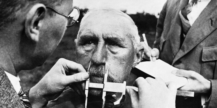 مقامات نازی در 1 ژانویه 1941 از کولیس برای اندازه‌گیری بینی یکی از قومیت‌های آلمانی استفاده می‌کند. نازی‌ها یک سیسم شبه‌علمی اندازه‌گیری صورت برای تعیین نژاد توسعه داده بودند. 
Hulton-Deutsch Collection / CORBIS / Corbis via Getty Images